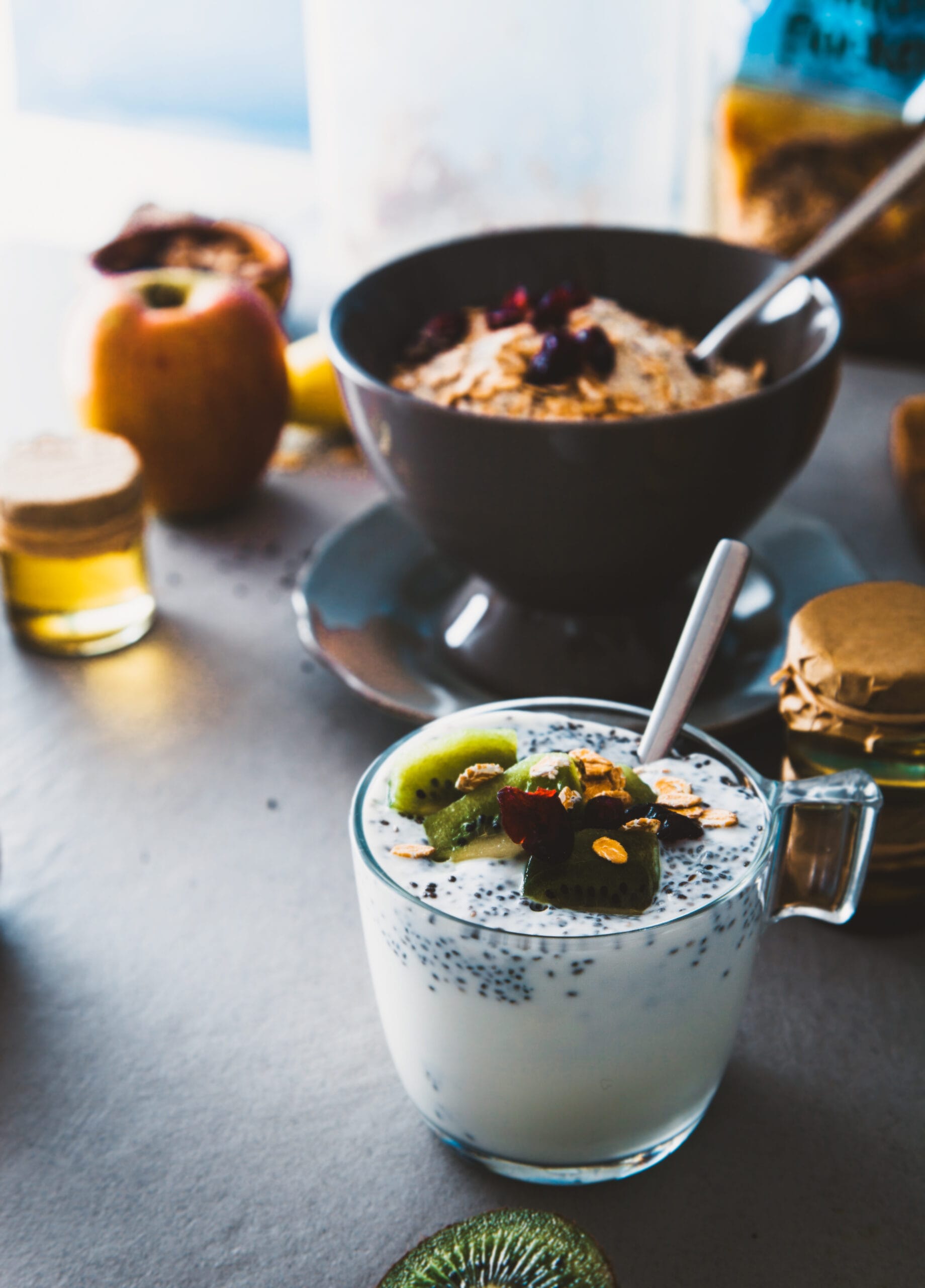 Chia pudding met fruit en granen naast een kom ontbijtgranen en verse ingrediënten
