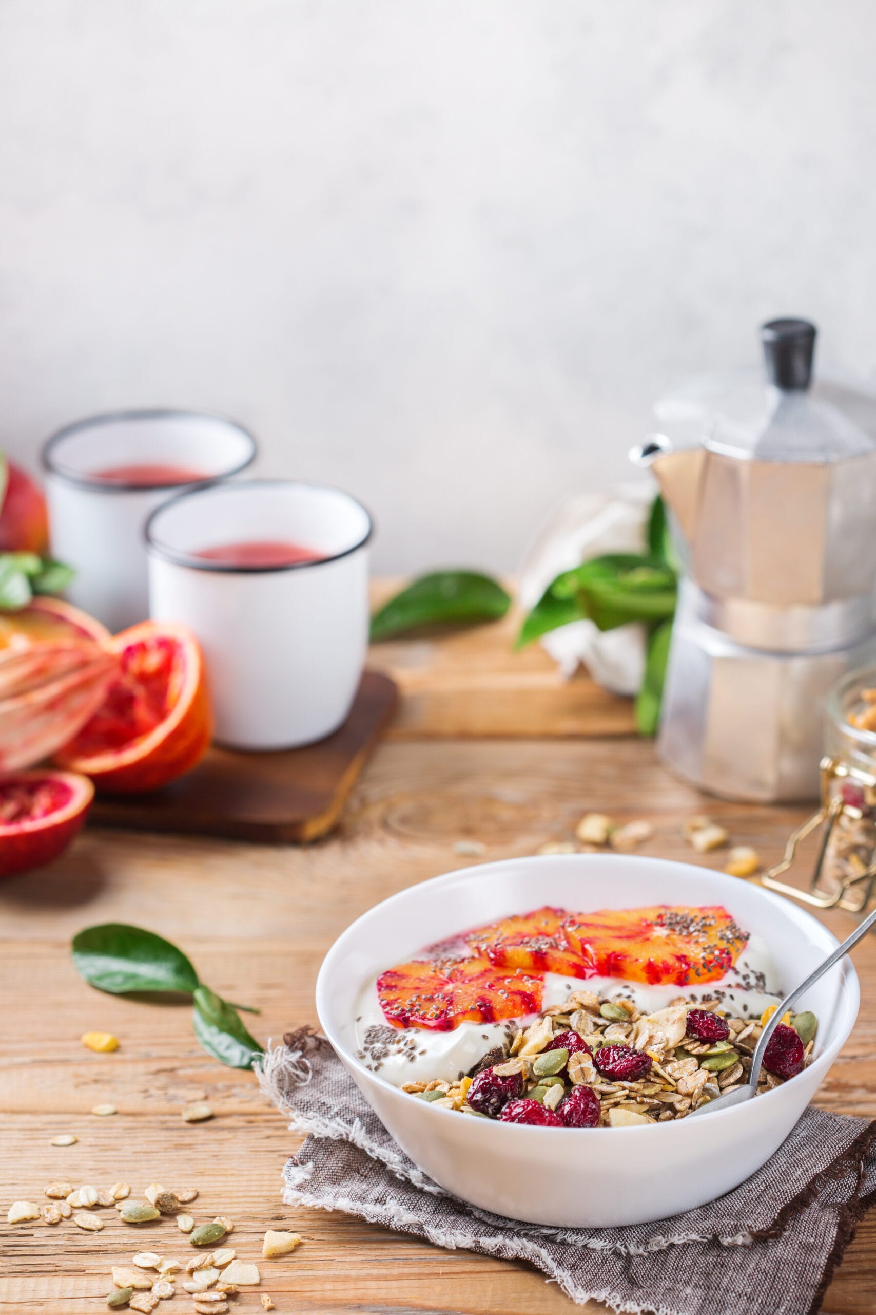 Kom yoghurt met granola, zaden en vers rood fruit op een houten tafel