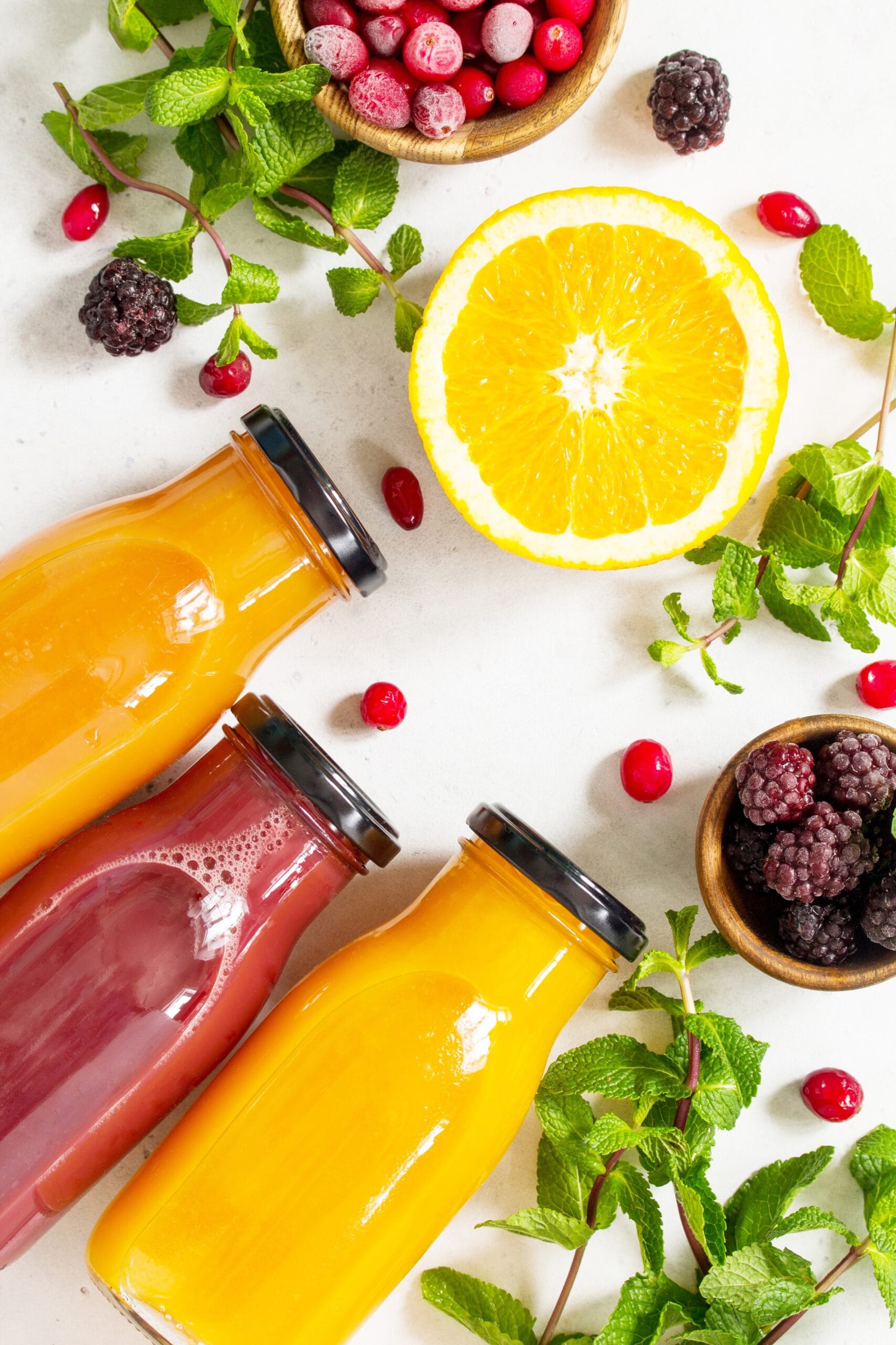 Verse geperste sappen met citrus, bessen en munt op lichte achtergrond